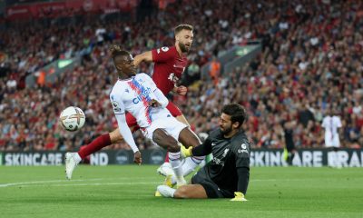 Wilfried Zaha of Crystal Palace has a shot saved by Alisson Becker of Liverpool as Nat Phillips watches on. (Photo by Clive Brunskill/Getty Images)